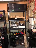 Black plastic shelving unit assembled with multiple shelves and miscellaneous items stored on it.