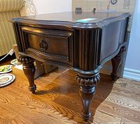 Front angle view showing side table with carved legs, drawer with metal ring pull, and dark wood finish.