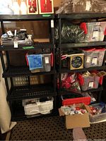 Photo showing two black plastic utility shelving units with contents removed, revealing grid-patterned shelves and supporting legs.