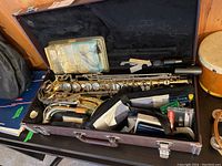 Open hard shell case showing saxophone body and accessories inside