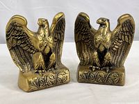 Pair of brass eagle bookends showing front and slightly angled views with details of feathers, beak, and base design.