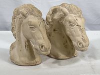 Pair of ceramic horse head bookends side by side showing overall shape and finish, with visible distress marks.