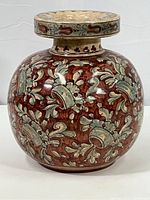 Front view of ceramic vase showcasing floral and scroll pattern in red, blue-green, and beige glaze.
