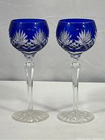 Pair of cobalt blue crystal wine goblets with cut to clear detailing, photographed front-facing to show overall shape and color depth.
