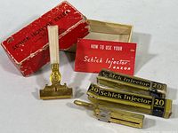 Vintage Schick Injector Safety Razor with ivory handle, original red box, instruction leaflet, and refill blade boxes arranged together.