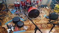 Large area rug partially visible under drum set, showing floral pattern and colors.