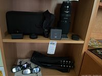 Overall shot of telephoto lens, speaker, lens pouch, small items on top shelf and tripod plus glasses on bottom shelf