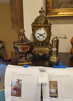Brass clock centered on shelf with glass dish and pepper mill to sides
