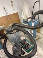 Overall view of Jet dust collector with connected hoses and metal barrel dust collector tank with accessibility hose attachments on floor.