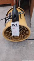 Front view of yellow ventilator heater showing protective grille and attached MaxSold tag with lot number and description.