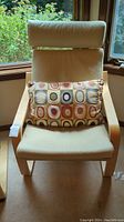 Front view of Ikea chair with beige cushions and decorative circular pattern lumbar pillow showing overall condition and style.