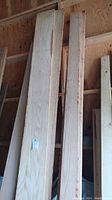 Three oak boards leaning against shop wall