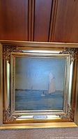 Full front view of framed painting showing gold ornate frame and sailboat scene