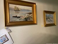 Overview of both framed paintings hanging on wall.