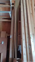 Vertical view of multiple long dimensional lumber pieces leaning against wall.