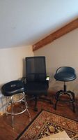 Photo showing three stools: an office chair with mesh back, a black bar stool with chrome legs, and a Roc-N-Soc drum stool.