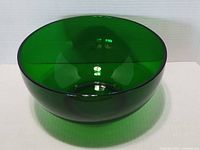 Front angle of a deep green large art glass bowl showing the vibrant emerald color and smooth glass surface.