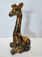 Front view of a ceramic giraffe figurine with detailed safari animal print patterns including zebra stripes and leopard spots.