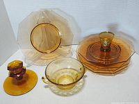 Photo showing all items including the stacked octagonal plates, candle holder, and two unique cups.