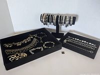 Main view showing multiple silver tone bracelets displayed on stands and trays
