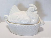 Front angle of vintage milk glass soup tureen with hen lid on nest-patterned base
