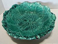 Front side view of the cabbage leaf dish showing leaf texture and glossy green glaze.