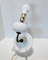 Photo of vintage milk glass electric wall lamp with visible hobnail texture, bulb socket, and curved arm.