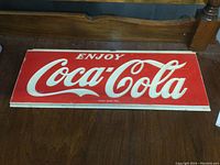 Front view of vintage Coca-Cola plastic sign on wooden surface