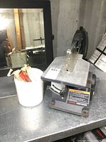 Photo of Sears Craftsman scroll saw on metal workbench with bucket filled with extra blades next to it.