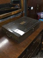 Closed view of vintage wooden cutlery chest showing metal side handle and latch, surface scratches visible