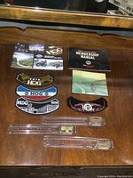 Full display of all Harley Davidson HOG items including patches, pins in packaging, manuals, and brochures.
