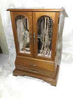 Front view of vintage wooden jewelry box with two mirrored glass doors and brass handles.