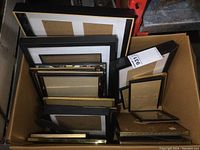 Box containing various picture frames stacked vertically, showing sizes from small to large with black and gold finishes.
