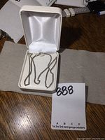 Sterling silver chain necklace inside a white jewelry box on a wooden surface.