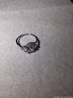 Sterling silver ring with a large center stone, two medium-sized stones on either side and smaller stones along the band sides, shown from an angle.