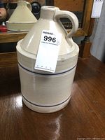 Front angle showing the jug's conical top, handle, and blue bands. Jug size approximately 12 inches tall with visible small chip on upper rim.