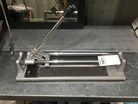 Overall view of the 21-inch Rona tile cutter showing the handle with black grip, metal base, and rails.