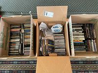 Three open boxes filled with CDs and DVDs