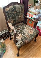 Front angled view showing carved dark wood frame, floral fabric upholstery with wear, and cabriole legs.