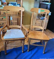 Pair view showing one captain chair with arms and one armless chair, both with lyre motif backs and seat pads