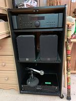 Front view of black cabinet showing receiver, speakers, microphone, and equalizer