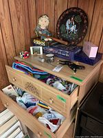 Full dresser with drawer open showing Lego pieces in plastic bags, plus items on top including Rubik's Cube, games, skipping rope, tennis balls, fabric doll, decorative plate, and other small items.