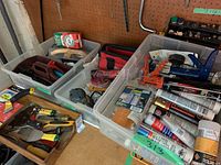 Overview of bins containing hand tools, sandpaper, sealants, scrapers, sanding supplies.