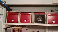 Four Omega watch boxes (three red, one black) lined up on shelf