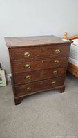 Front view of oak blanket chest showing four drawers and brass bail pulls