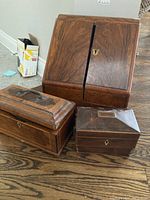Three walnut-veneered boxes grouped on hardwood floor