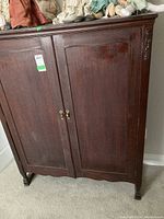 Front view of antique wooden linen cupboard showing two paneled doors with brass handles and keyholes.