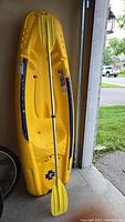 Kayak upright in garage with paddle leaned against it