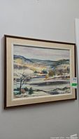 Photo of framed signed original winter landscape painting hanging on wall, showing full artwork and frame.