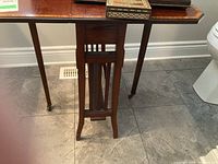Front view showing woodworking details, inlaid top and leg style of antique wooden table